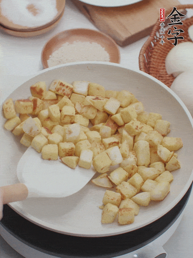 起鍋熱油，倒入饅頭丁，小火煎至蛋液凝固定型再翻面，饅頭丁部煎至金黃時(shí)盛起待用。